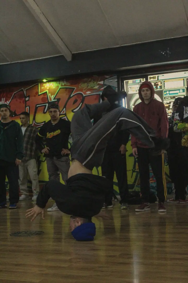 Un bboy apoyado en la cabeza frente a la ronda de bailarines