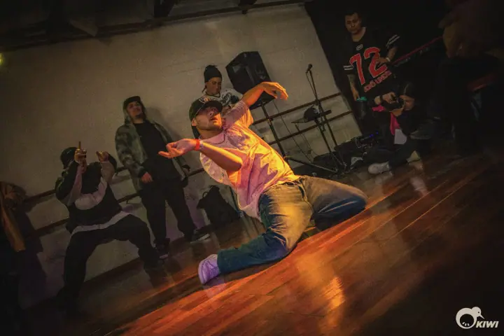 Un bailarín en el piso en plena batalla, con el público mirando alrededor